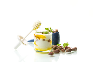 homemade yogurt with kiwi, honey and nuts in a glass, isolated on white background