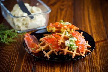 vegetable potato waffles with spread and lightly salted red fish, in a plate on a wooden table
