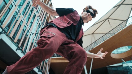 Low angle of asian attractive hipster pose at camera surround by mall. Portrait of break dance choreographer looking at camera while dancing in hip hop style. Outdoor sport 2024. Hiphop.