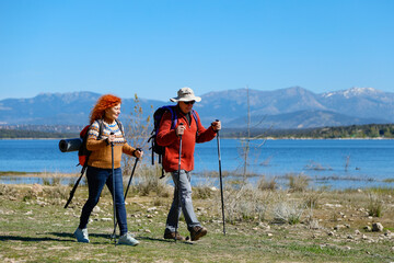 Senior couple hiking near lake with mountain view enjoying nature