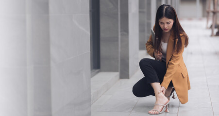 A successful businesswoman hurts her ankle while rushing to a meeting with business people of...