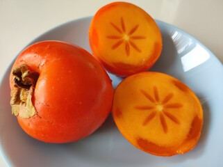 Persimmon (Diospyros kaki) orange fruit in blue dish