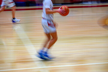 High School Basketball with motion blur showing the speed and movement of the young boys playing...