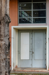 A section of a building with a tree trunk, a window and a door
