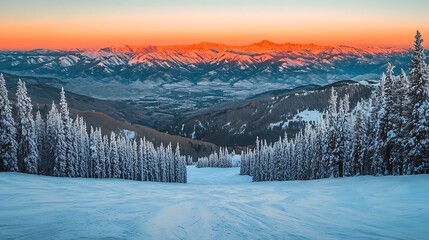 A wide-angle shot of the alpine mountains as the sun sets, casting a warm orange glow over the snowy ridges and creating dramatic contrasts of light and shadow 