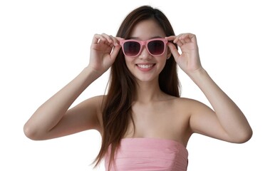 Fototapeta premium A smiling Asian woman with long brown hair wears pink sunglasses and a strapless pink top against a white background.