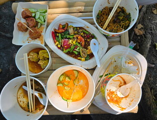 Leftover food is placed together on bamboo table. Food is packed in disposable plates and cups. Leftover food is thrown away as trash. Dirty, biodegradable disposable tableware from environmentally 
