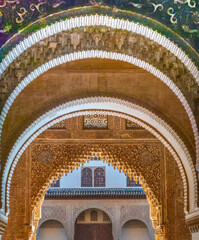 Obraz premium Series of arabesque arches leading to a courtyard among the ruins of the historic Nazarid Palace, the Alhambra complex, Granada, Andalusia, Spain