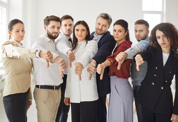 Group of business people in an office shows thumbs down or dislike gesture, expressing dissatisfaction. Team focuses on collaboration and teamwork to address challenges and improve business outcomes.