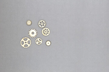 Set of various wooden gear wheels on the grey background.