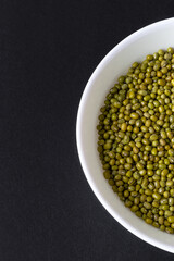 Top view of mung beans  in white bowl on black background