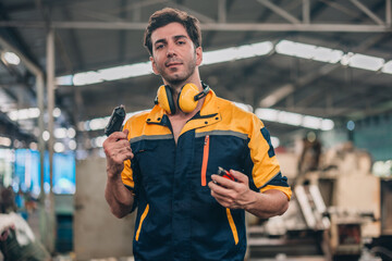 Skilled Worker in Industrial Workshop Poses Confidently With Tools in Hand