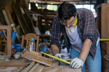 modern caucasian craftsman using tablet computer doing DIY wood furniture and repair woodcraft at the carpentry workshop.