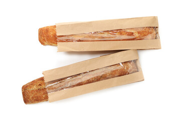Fresh baguettes in paper bags isolated on white, top view
