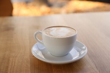 Cup of aromatic coffee on wooden table in cafe, closeup