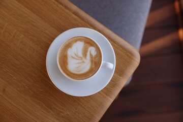 Cup of aromatic coffee on wooden table in cafe, top view