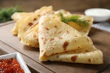 Delicious crepes and red caviar on table, closeup