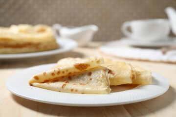 Tasty crepes on wooden table, closeup view