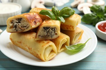 Delicious rolled crepes with mushrooms and basil on light blue wooden table, closeup