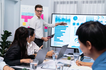 Presentation in office or meeting room with analyst team utilizing BI Fintech to analyze financial data. Businesspeople analyzing BI dashboard power display on TV screen for strategic planning.Prudent