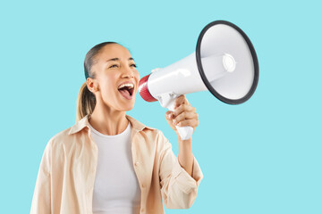 Happy girl on blue background shouting into loudspeaker, close-up. Young woman with megaphone in hands. Concept hot news, call to action, affectionate anniversary, woman megaphone speaking
