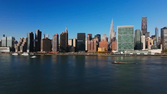 Tugboat sails east on East River, featuring iconic skyscrapers including headquarters of the United Nations in Turtle Bay neighborhood of Midtown Manhattan