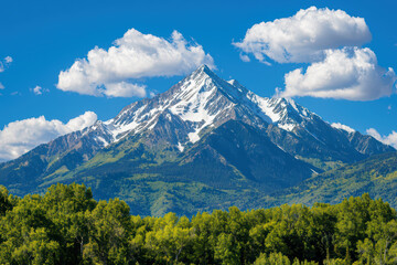Fototapeta premium Majestic mountains rise under bright blue sky, surrounded by lush greenery