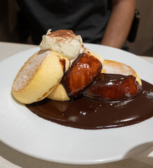 Nahaufnahme von fluffigen Soufflé-Pfannkuchen, die mit Puderzucker bestreut und mit Schlagsahne serviert werden mit Heidelbeeren und Schokosauce, gebackenes Dessert
