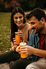 Two people bonding over snacks and beverages on a cozy picnic blanket in the park