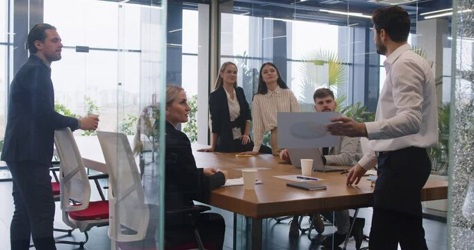 Group mentoring in modern office, confident leader, businessman executive mentor talking to employees during corporate briefing in boardroom, boss explaining work plan, finance result document 