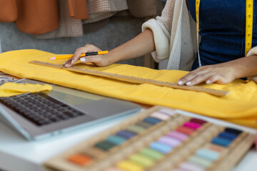 A woman who is running an online clothing business and is also a designer, working on designing...