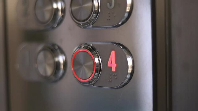 Unrecognized man pressing button of elevator with the polished metal surface. An elevator panel lights up while ascending to the fourth floor. Modern hotel concept.