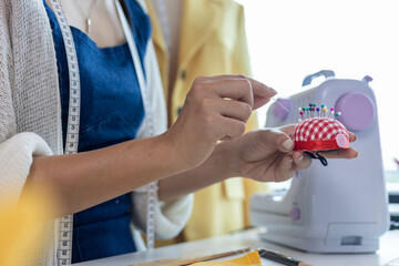 Fototapeta premium A woman who is running an online clothing business and is also a designer, working on designing clothes and preparing them to be packed in boxes to be delivered to customers.