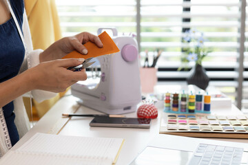 A woman who is running an online clothing business and is also a designer, working on designing...