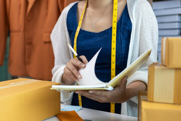 A woman is sitting at a desk with a box in front of her. She is writing on a piece of paper with a pencil. The scene suggests that she is working on a project or task related to the box