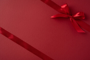 A vibrant red ribbon elegantly tied on a deep red surface, symbolizing love and elegance. This minimalistic image is perfect for Valentine's Day, gift giving, or romantic themes