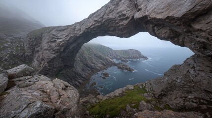 Obraz premium Misty coastal arch rock formation over ocean cove.