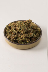 in a bowl dry flowers of medical cannabis. On a light background