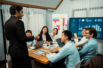 Diverse group of business analyst team analyzing financial data report. Finance data analysis chart and graph dashboard show on TV screen in meeting room for strategic marketing planning. Habiliment