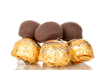 Several chocolate candies wrapped in gift paper, close-up, isolated on a white background.
