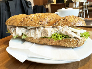 Whole grain tuna sandwich with lettuce and onion on white plate