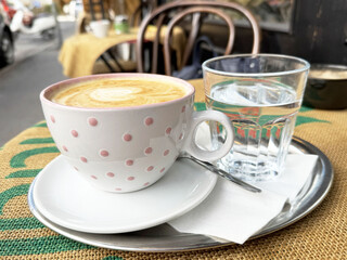 Polka dot latte and water glass on outdoor cafe table