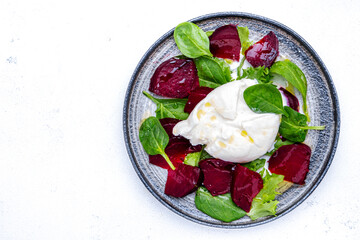 Tasty salad with burrata cheese, baked beets,  spinach and olive oil, white background, top view