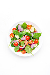 Spring healthy vegetable salad with spinach, tomatoes, cucumber, red onion and olive oil. White background, top view