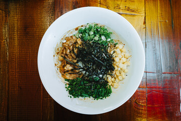 A bowl of Japanese Ramen with toppings: Sliced meat, seaweed, corn, and green onions