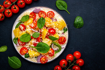 Nourishing salad with grilled chicken, couscous, tomatoes, onion, spinach and orange. White background, top view