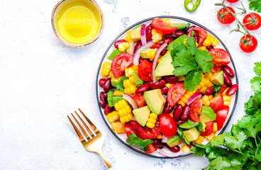 Corn salad with red beans, avocado, tomatoes, onion and cilantro. White background, top view