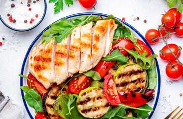 Grill chicken salad with spinach. grilled paprika, zucchini, eggplant, fresh tomatoes and arugula on white background, top view