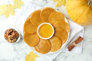 Tasty pumpkin pancakes served on white marble table, flat lay