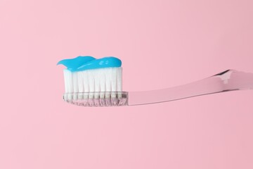 Toothbrush with toothpaste in air on pink background, closeup